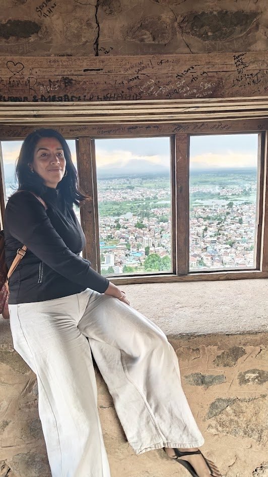 Varuna Shunglu sitting at the top of Hari Parbat fort, overlooking Srinagar city through an ancient stone window